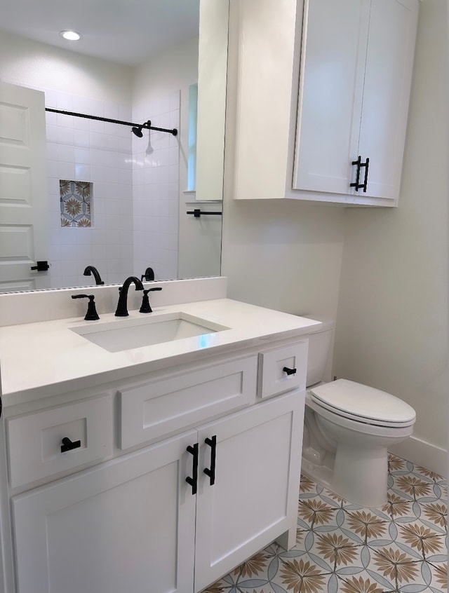 bathroom with vanity, toilet, tiled shower, and tile patterned floors