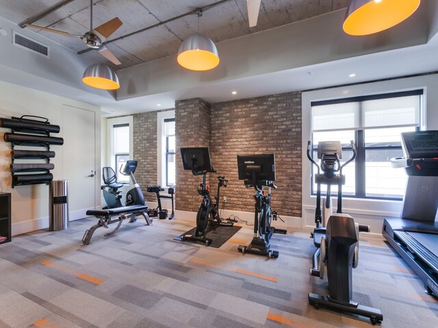 gym with plenty of natural light, brick wall, ceiling fan, and carpet flooring