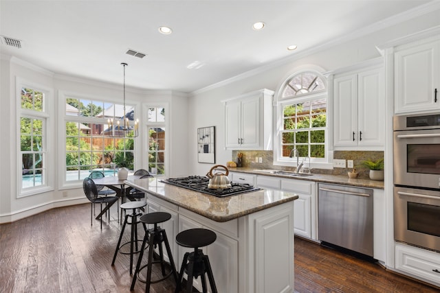 kitchen featuring a center island, light stone countertops, stainless steel appliances, sink, and dark wood-type flooring