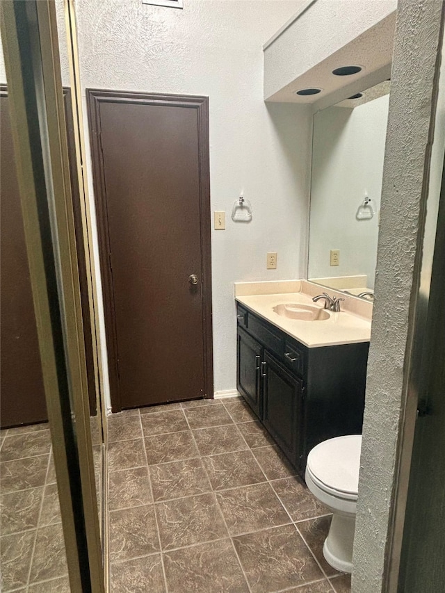 bathroom featuring vanity, tile patterned flooring, and toilet