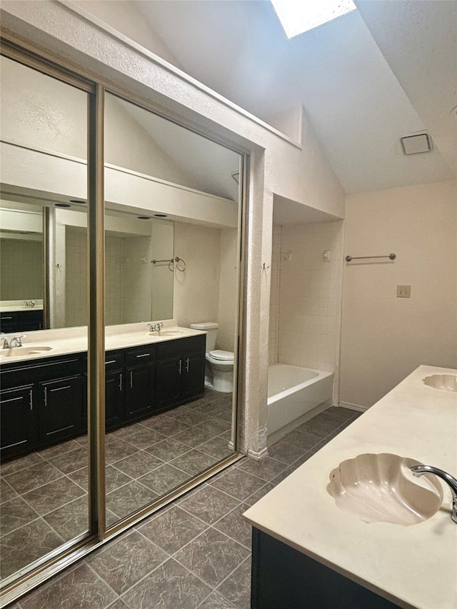 full bathroom featuring vanity, tile patterned flooring, lofted ceiling with skylight, and toilet