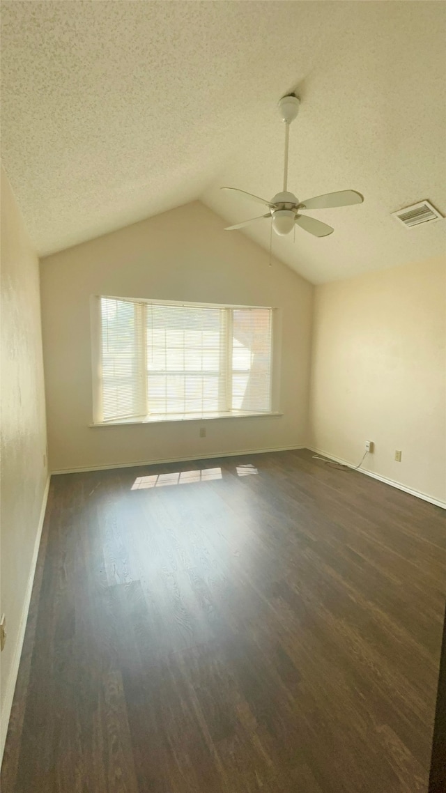 spare room with ceiling fan, vaulted ceiling, a textured ceiling, and dark hardwood / wood-style flooring