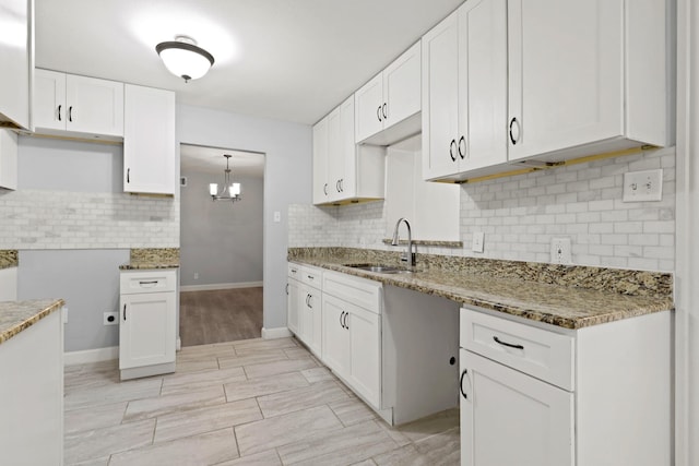 kitchen featuring white cabinets, decorative backsplash, stone counters, and sink