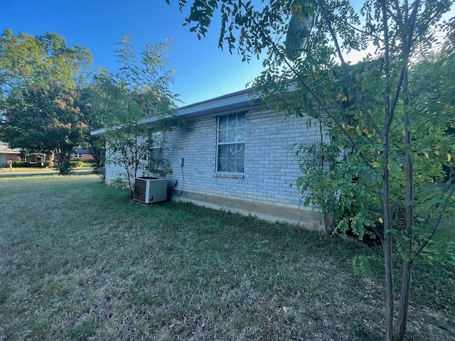 view of side of home featuring a lawn and central AC unit