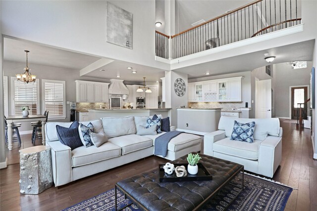 living room featuring a chandelier, a towering ceiling, and dark hardwood / wood-style floors