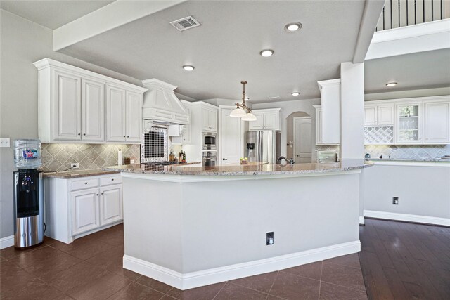 kitchen with white cabinets, appliances with stainless steel finishes, backsplash, and a kitchen island with sink