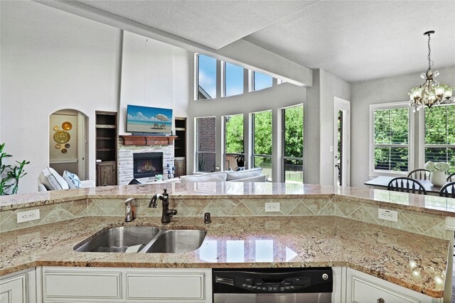 kitchen featuring white cabinetry, sink, stainless steel dishwasher, and a notable chandelier