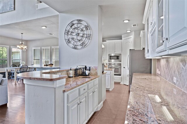 kitchen featuring tasteful backsplash, white cabinetry, stainless steel appliances, and an inviting chandelier