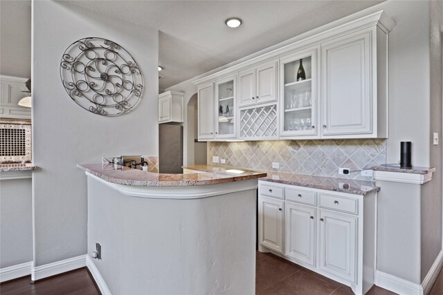 kitchen with kitchen peninsula, decorative backsplash, dark hardwood / wood-style floors, and white cabinetry