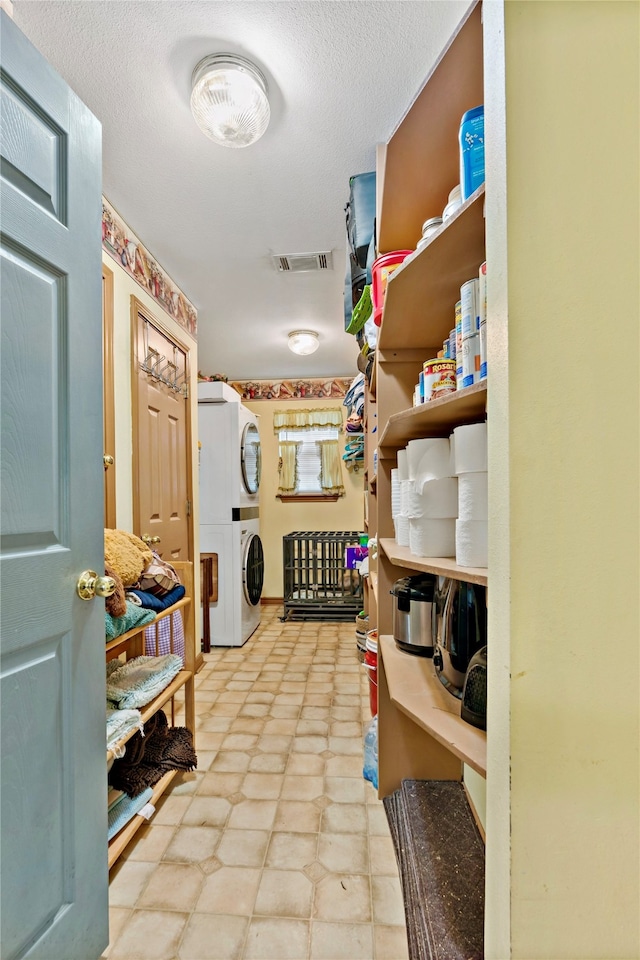 pantry featuring stacked washer and clothes dryer