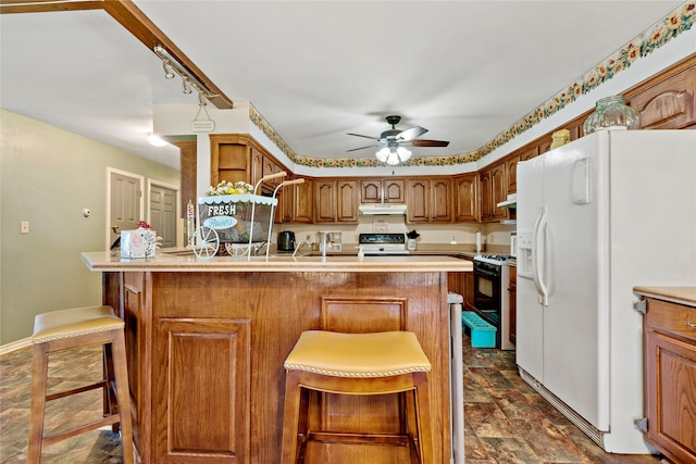 kitchen featuring ceiling fan, white appliances, and a breakfast bar area