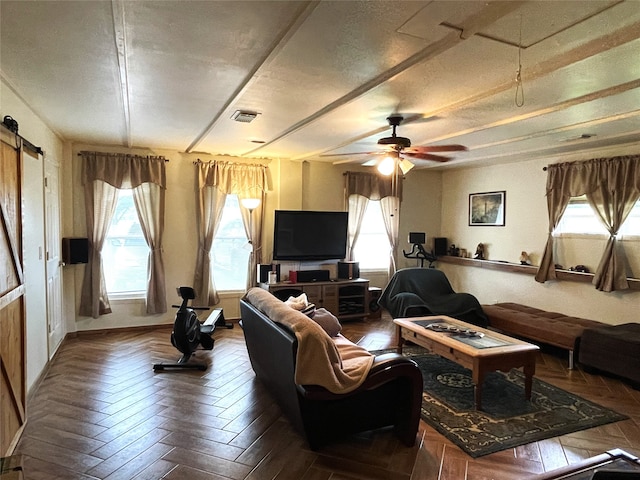 living room featuring parquet floors, a barn door, ceiling fan, and a textured ceiling