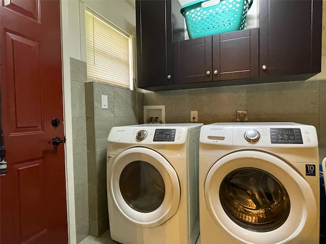 clothes washing area with cabinets and separate washer and dryer