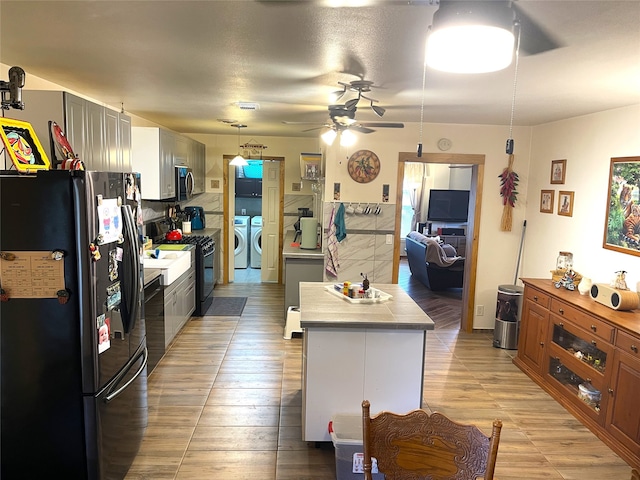 kitchen featuring washer and dryer, stainless steel appliances, ceiling fan, gray cabinetry, and light hardwood / wood-style floors