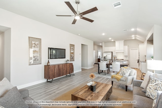 living room with lofted ceiling, ceiling fan, and light wood-type flooring