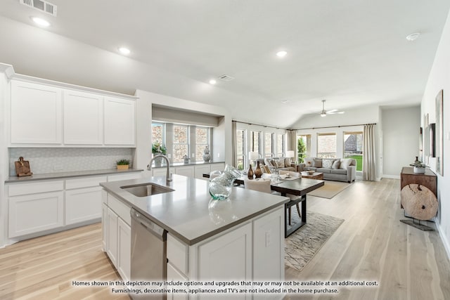 kitchen with light hardwood / wood-style flooring, a center island with sink, sink, vaulted ceiling, and stainless steel dishwasher