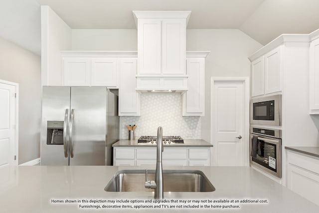 kitchen with white cabinetry, stainless steel appliances, sink, decorative backsplash, and lofted ceiling