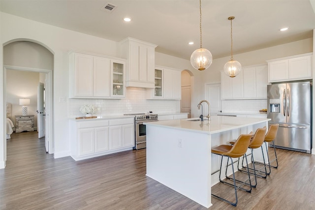 kitchen featuring a kitchen island with sink, hardwood / wood-style floors, white cabinets, and appliances with stainless steel finishes