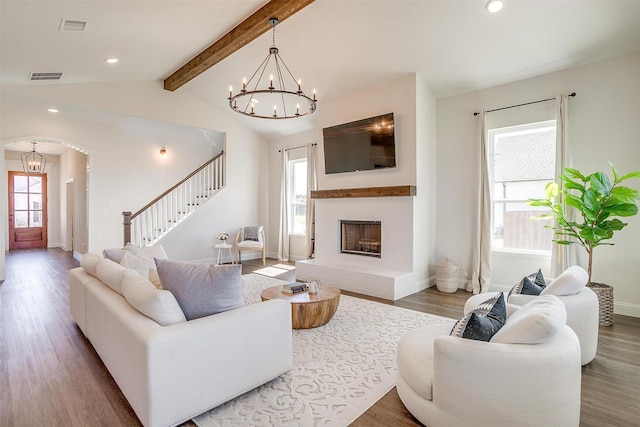 living room with a chandelier, wood-type flooring, and lofted ceiling with beams