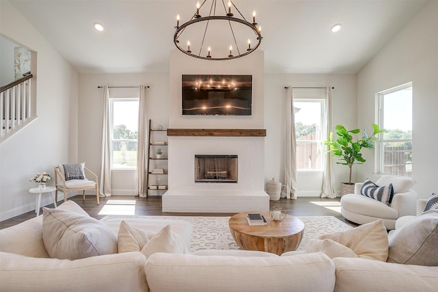 living room featuring a fireplace, wood-type flooring, lofted ceiling, and a notable chandelier