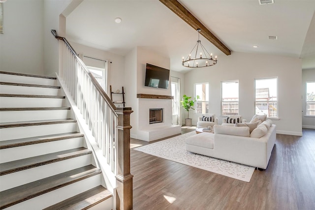 living room featuring dark wood-type flooring, lofted ceiling with beams, and an inviting chandelier