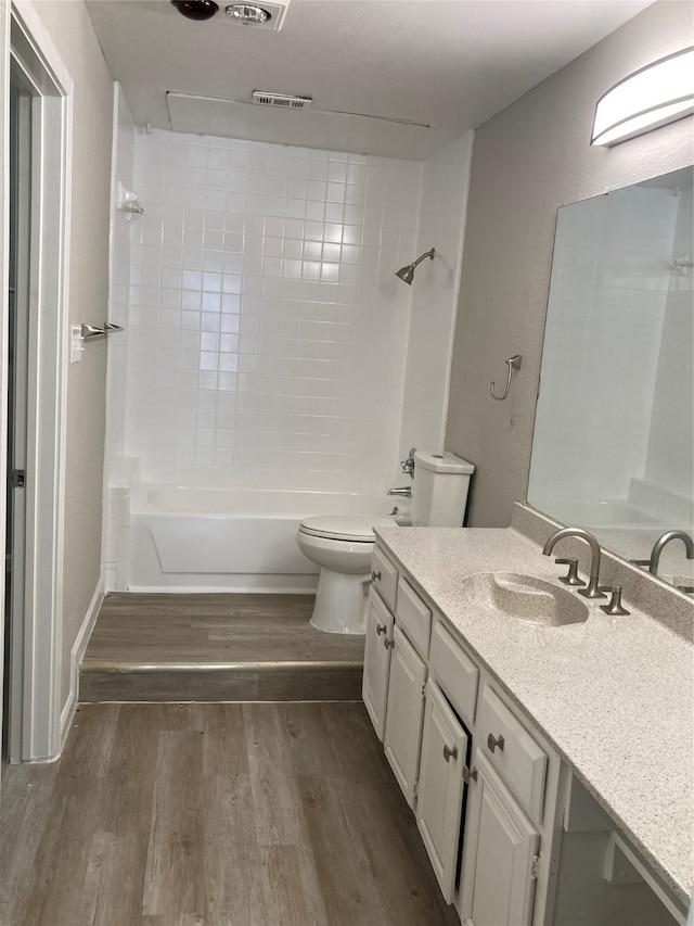 full bathroom with wood-type flooring, vanity, tiled shower / bath combo, and toilet