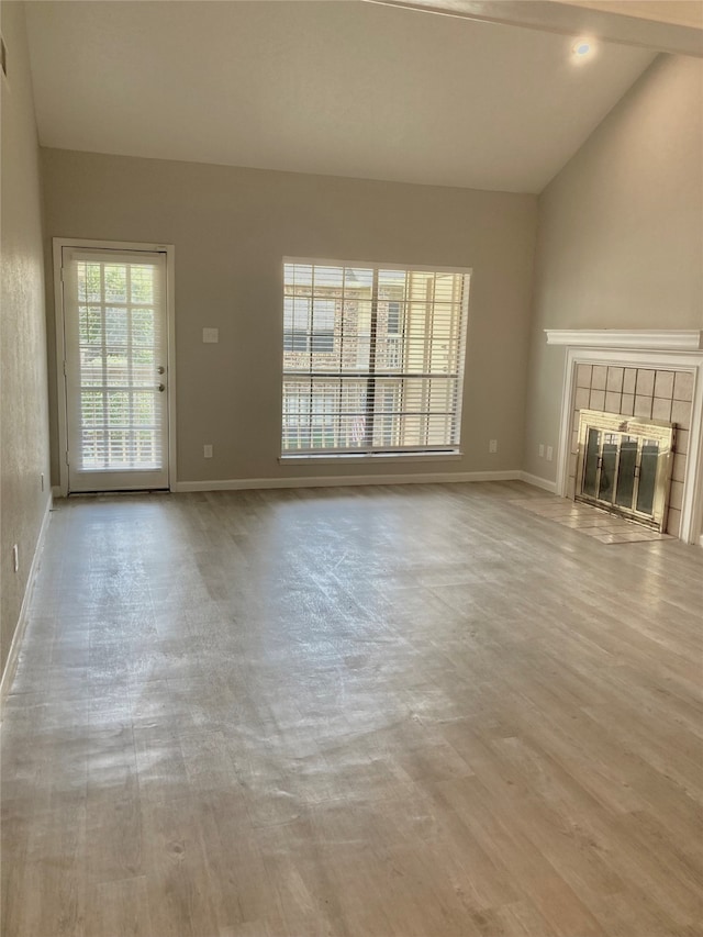 unfurnished living room with a fireplace, light wood-type flooring, and vaulted ceiling