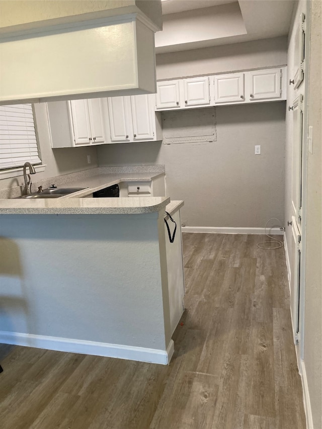 kitchen with kitchen peninsula, dark hardwood / wood-style flooring, sink, and white cabinets