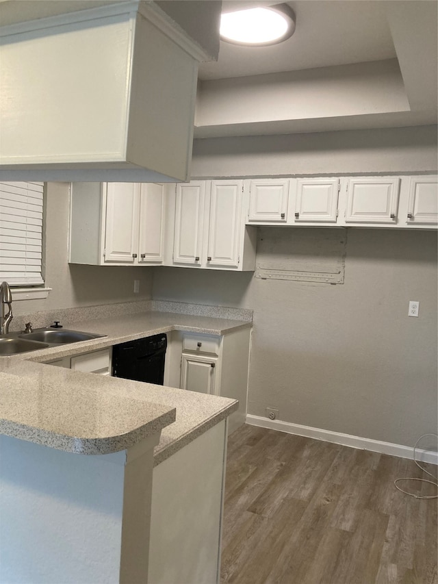 kitchen with sink, kitchen peninsula, dark wood-type flooring, white cabinetry, and black dishwasher