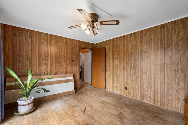 spare room featuring a ceiling fan, wood walls, and wood finished floors