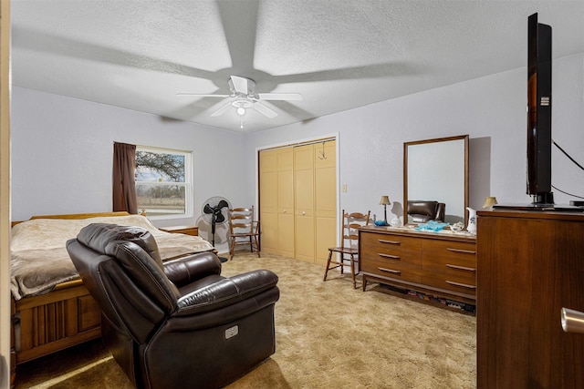 carpeted bedroom with a closet, ceiling fan, and a textured ceiling