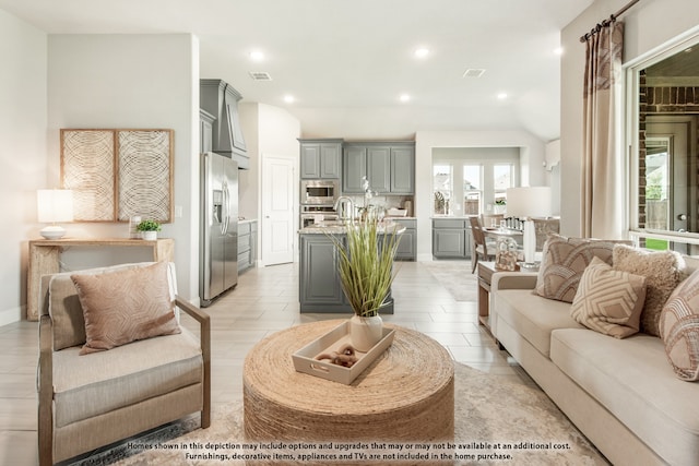 living room featuring light hardwood / wood-style floors, lofted ceiling, and sink