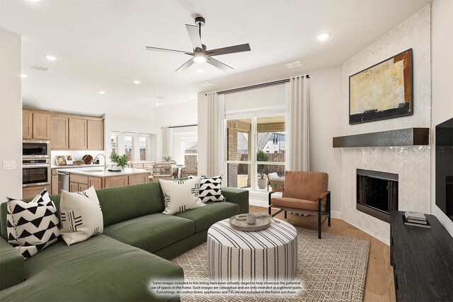 kitchen featuring light stone countertops, stainless steel appliances, gray cabinets, premium range hood, and a kitchen island with sink