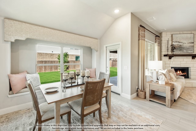 dining room with lofted ceiling and a stone fireplace