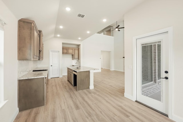 kitchen featuring light hardwood / wood-style flooring, light stone countertops, sink, vaulted ceiling, and ceiling fan