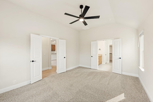 unfurnished bedroom with ceiling fan, connected bathroom, vaulted ceiling, and light colored carpet