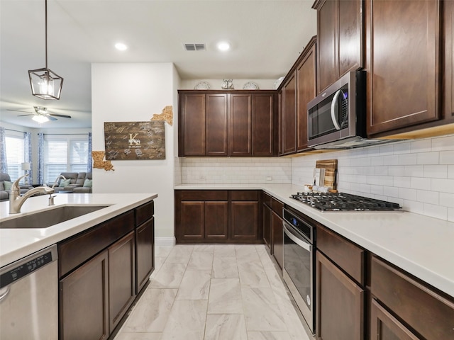 kitchen featuring pendant lighting, dark brown cabinets, sink, ceiling fan, and appliances with stainless steel finishes