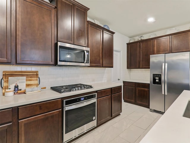 kitchen with stainless steel appliances, light tile patterned floors, dark brown cabinets, and tasteful backsplash