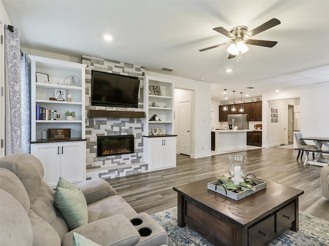 living room with ceiling fan, hardwood / wood-style floors, and a fireplace