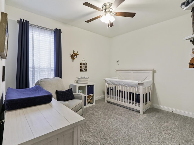 carpeted bedroom featuring a crib and ceiling fan