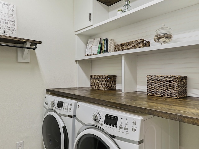 clothes washing area with washing machine and clothes dryer and cabinets