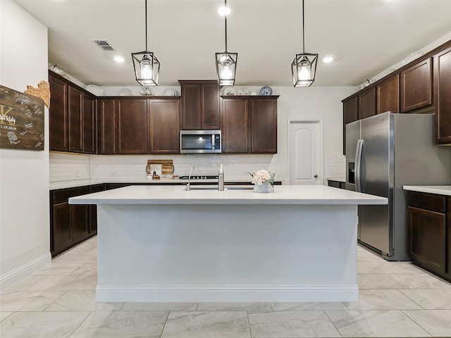 kitchen featuring appliances with stainless steel finishes, a center island with sink, and dark brown cabinetry