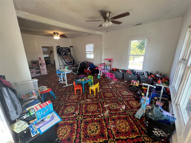 rec room with ceiling fan and a textured ceiling