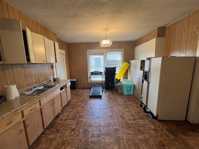 kitchen featuring light brown cabinetry, sink, pendant lighting, white fridge with ice dispenser, and a textured ceiling