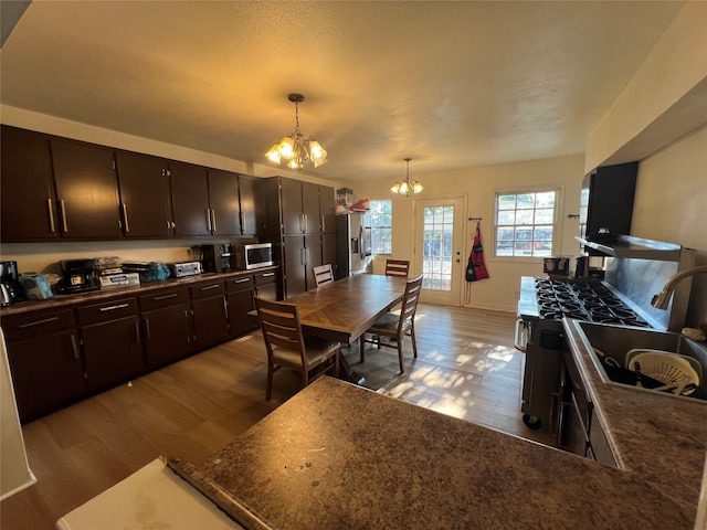 kitchen with appliances with stainless steel finishes, light hardwood / wood-style flooring, a notable chandelier, and pendant lighting