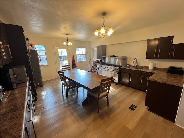 dining area featuring a textured ceiling, light hardwood / wood-style flooring, sink, and a notable chandelier