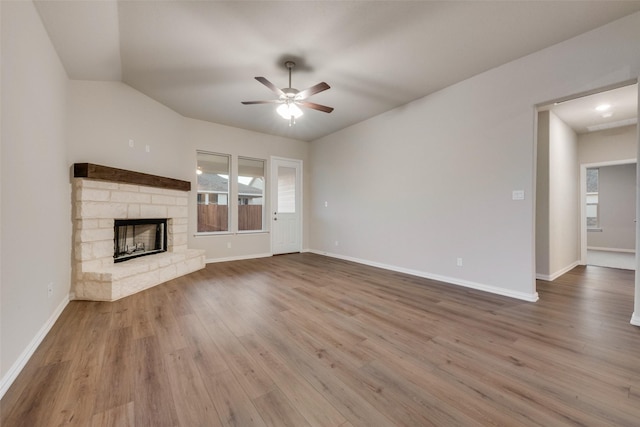 unfurnished living room featuring ceiling fan, a stone fireplace, and light wood-type flooring