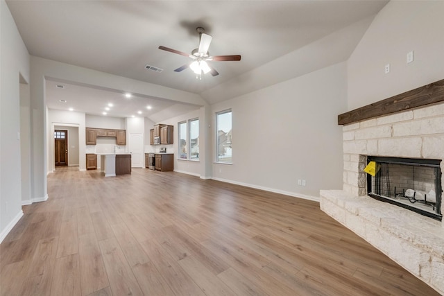 unfurnished living room with vaulted ceiling, ceiling fan, a fireplace, and light hardwood / wood-style floors