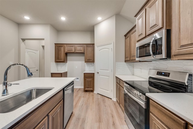 kitchen featuring sink, stainless steel appliances, light stone countertops, decorative backsplash, and light wood-type flooring