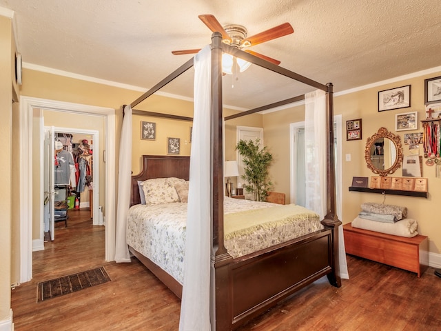 bedroom with ceiling fan, dark hardwood / wood-style floors, crown molding, and a textured ceiling